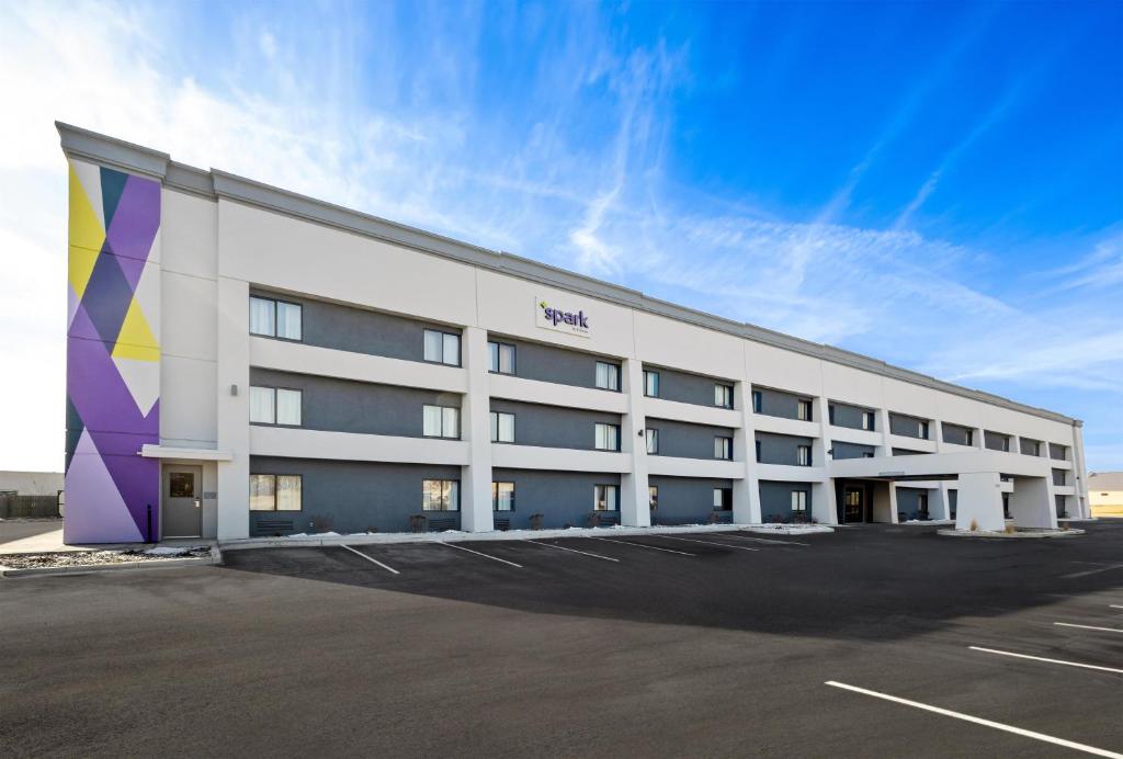 a large white building with a parking lot at Spark By Hilton Fort Wayne in Fort Wayne