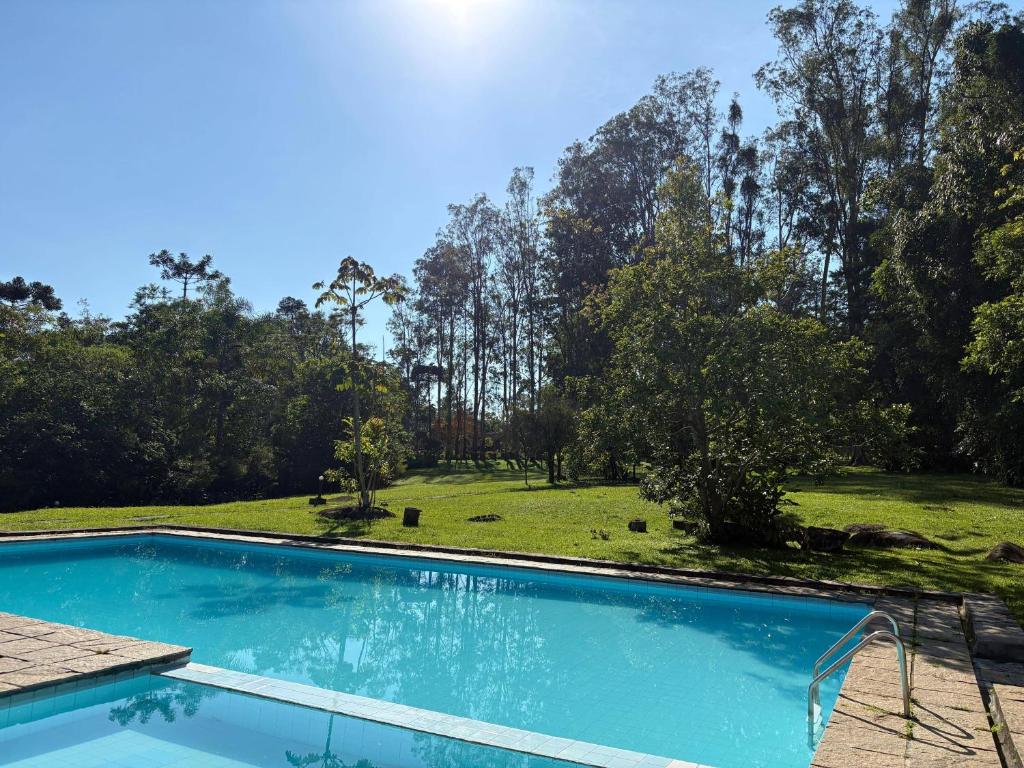 ein Swimmingpool vor einem Feld mit Bäumen in der Unterkunft Hotel Refazenda in Visconde De Maua