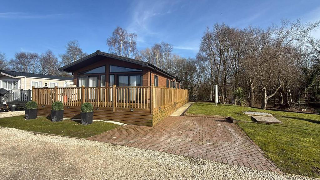 a small cabin in a yard with a fence at Cedar Lodge - 27 Sunset View in Crowle