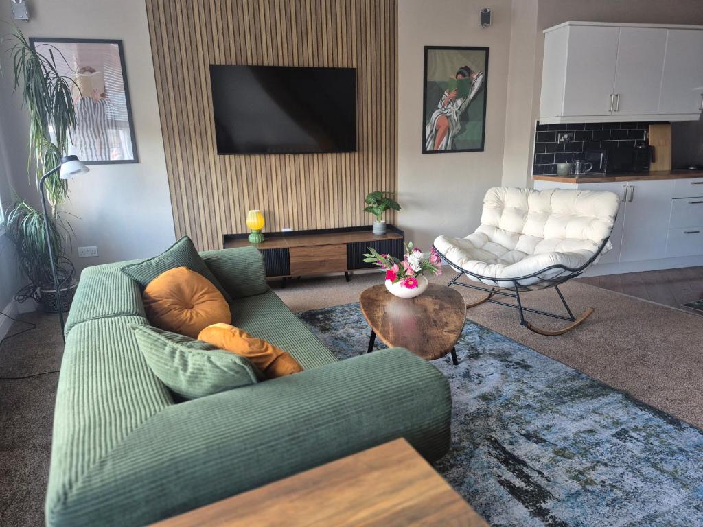 a living room with a green couch and a television at Sleep Eat Repeat Apartment in Macclesfield