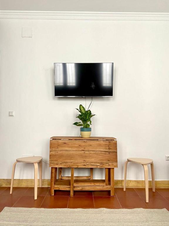 a tv on a wall with a table and two stools at Galteo Alameda in Ronda
