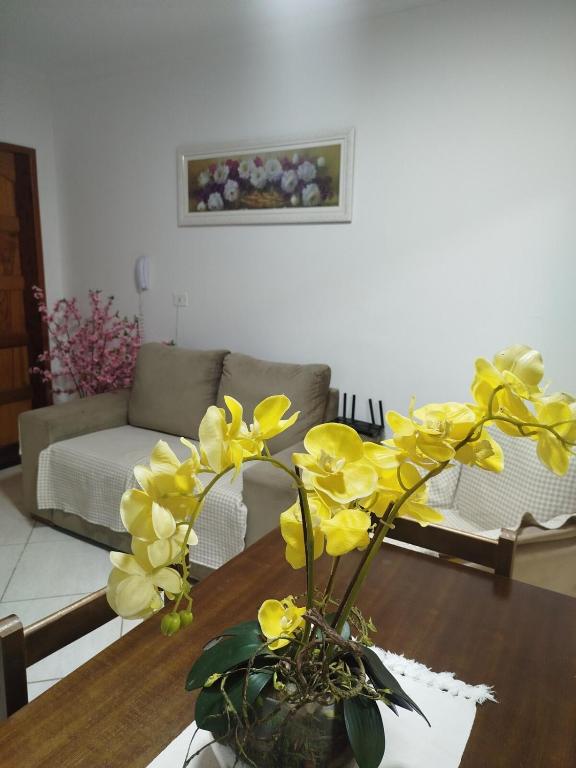 a vase with yellow flowers on a table in a living room at Casa Aconchego in São Carlos