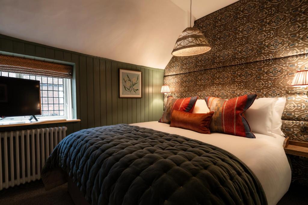a bedroom with a large bed with pillows at Bel and The Dragon-Cookham in Cookham