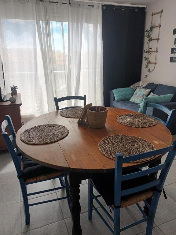 a wooden dining room table with chairs and a couch at Appartement les saladelles in Le Grau-du-Roi