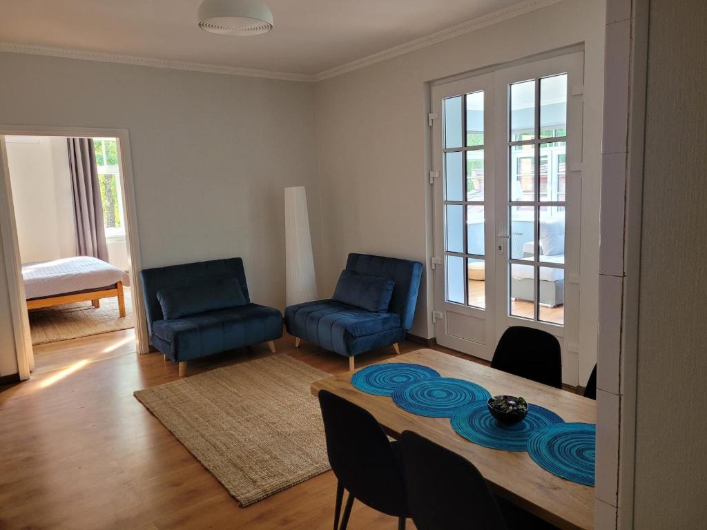 a living room with two blue chairs and a table at Apartamenti HUGO in Valmiera