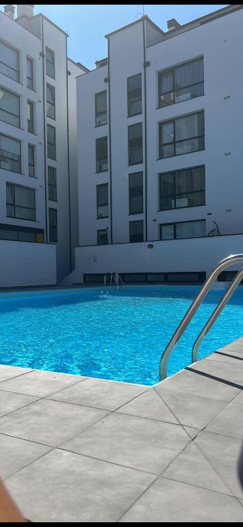 a swimming pool with blue water in front of buildings at Apartamento "Playa de Sada" in Sada