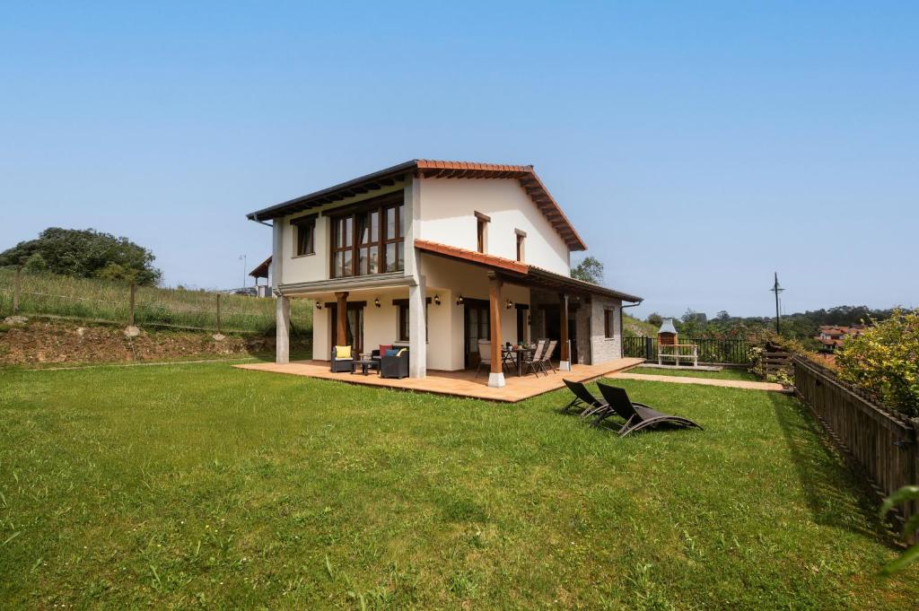 a small house with a green lawn in front of it at Villa Senda Llanes – Jardín, Terraza y Playa Cerca in Llanes