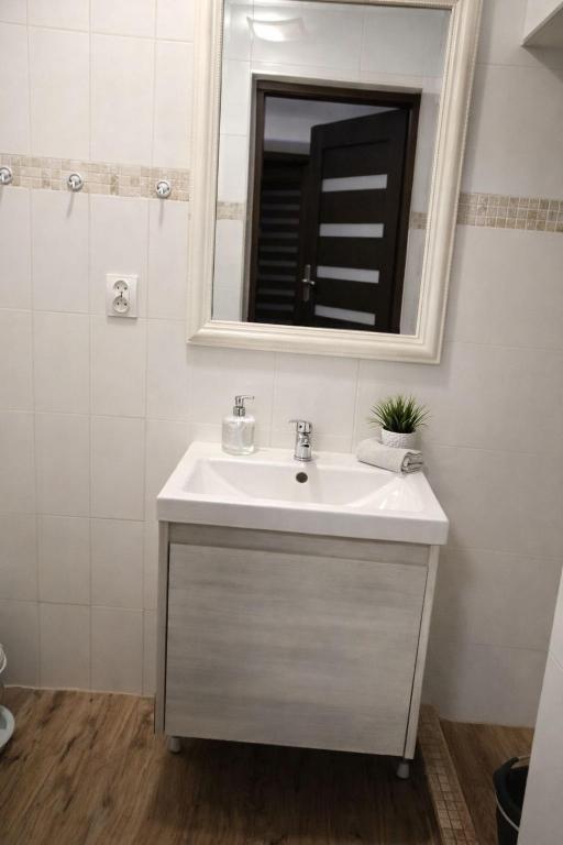 a white bathroom with a sink and a mirror at Apart NOVA in Raszyn