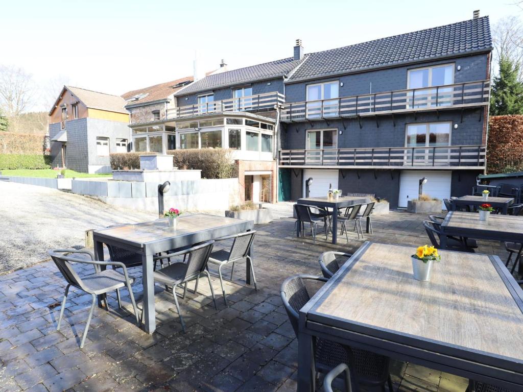 a patio with tables and chairs and a building at Le Grand Vallon in Polleur