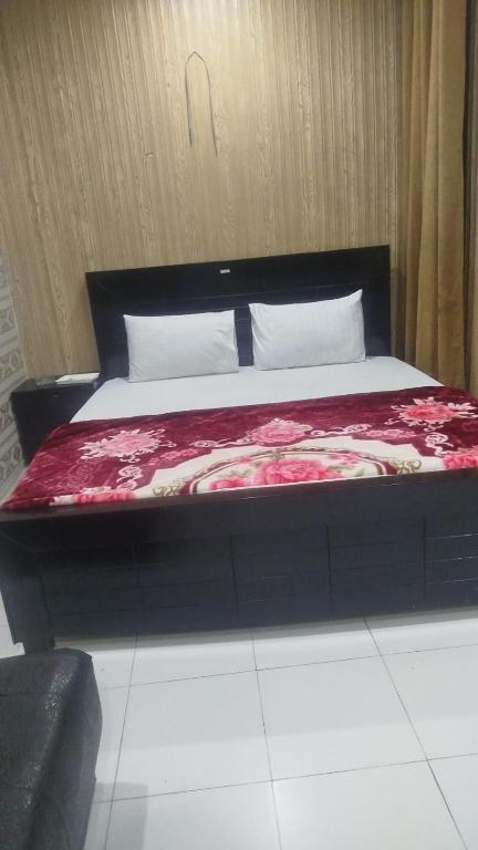 a bedroom with a bed with red sheets and white pillows at Palace inn Hotel in Dargai