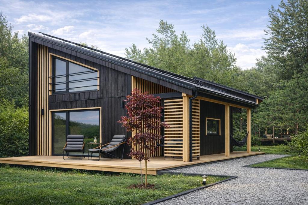 a small house with two chairs on a wooden deck at Przylesie Domki in Wysoczany