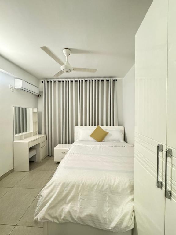 a white bedroom with a bed and a ceiling fan at Snapstay103 in Hulhumale