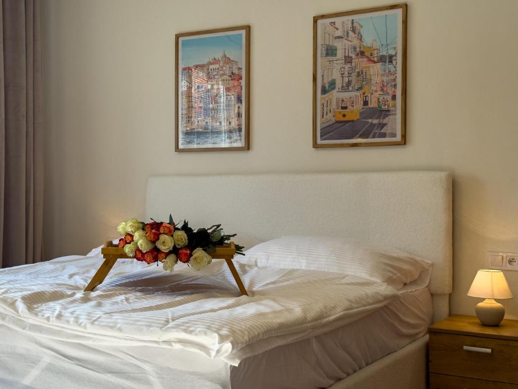 a white bed with a bouquet of flowers on it at The Minimalist Suite in Šurany