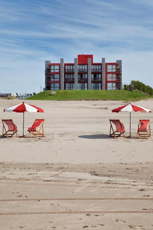 three chairs and umbrellas on a beach with a building at Altaplaya in Las Gaviotas
