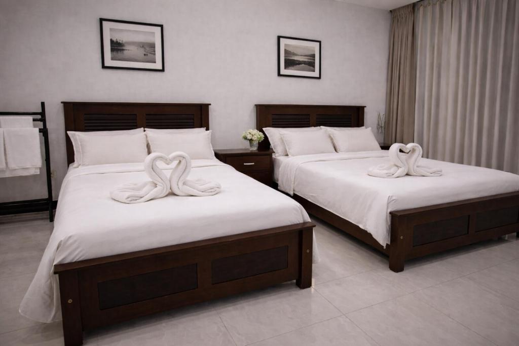 two beds with white towels on them in a bedroom at Emerald Sea Breeze - Madiha in Nikawatawana