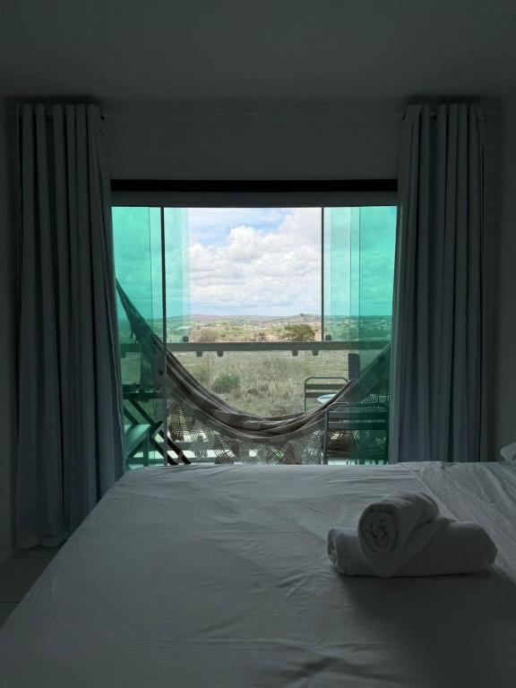 a bedroom with a bed and a large window at Flat Vila Monte Castelo in Gravatá