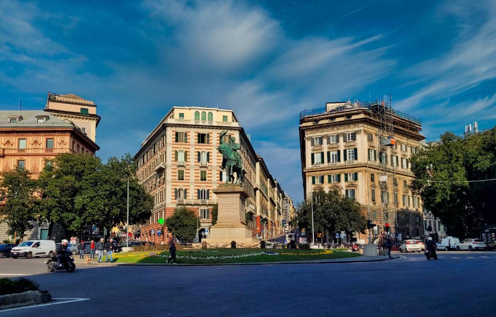 two buildings with a statue in the middle of a street at Le Due Piazze in Genoa