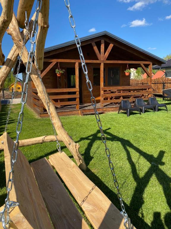 a swing in front of a log cabin at Domki pod Dębem in Wilkasy