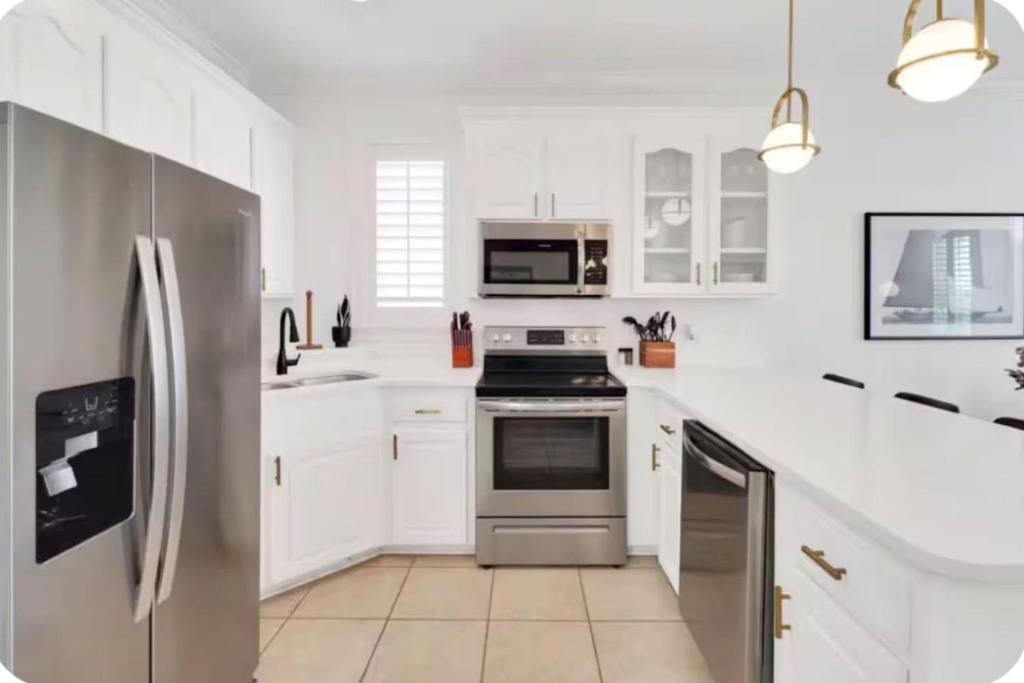 a kitchen with white cabinets and a stainless steel refrigerator at Simply Adventurous Too in Mexico Beach