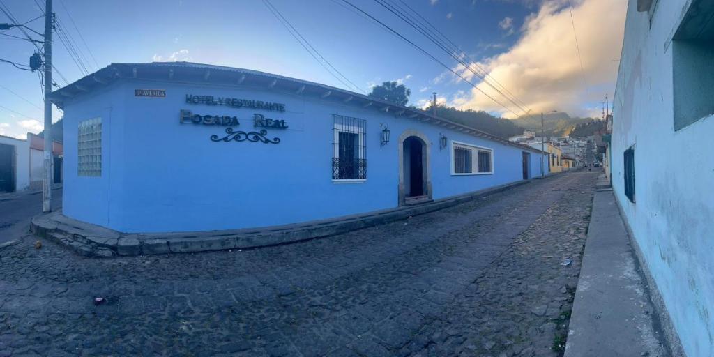 a white building with a sign on the side of it at Hotel y Restaurante Posada Real in Quetzaltenango