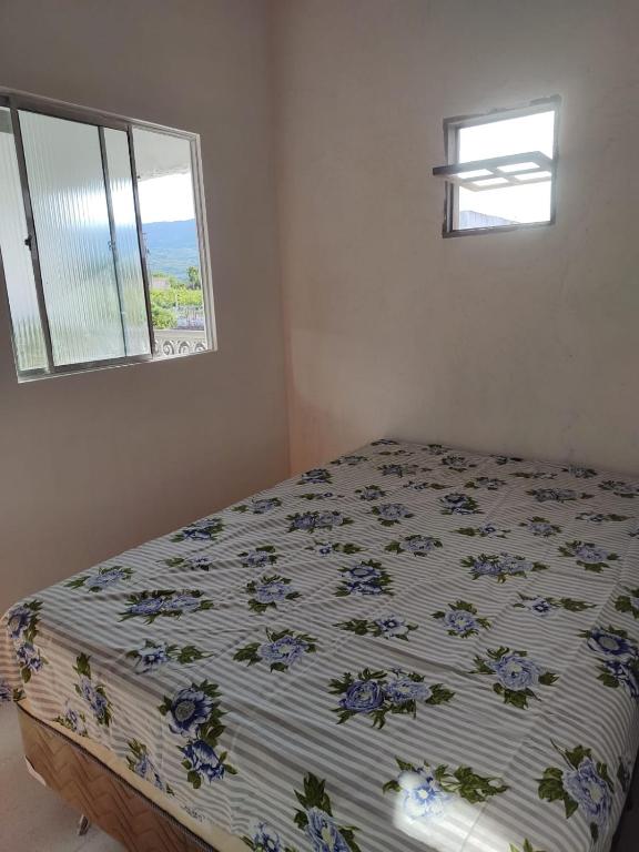 a bedroom with a bed with a floral bedspread and a window at Chácara Santa Teresinha Crato in Crato