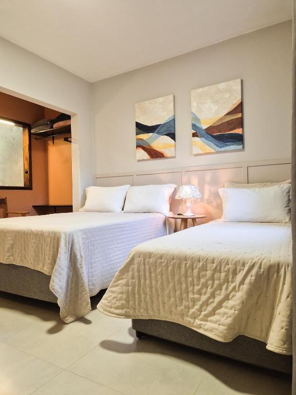 two beds in a room with paintings on the wall at Frieden Haus Hospedagem in Pomerode