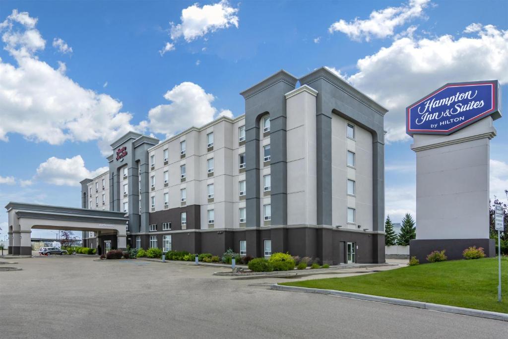 a hotel with a sign in front of a parking lot at Hampton Inn & Suites Edmonton/West in Edmonton