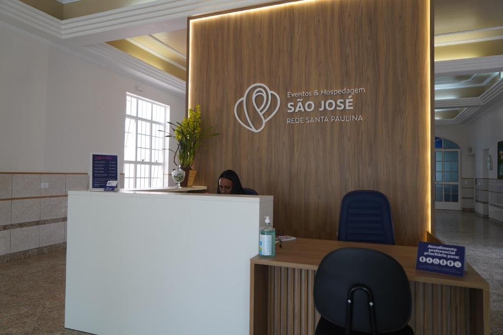 a reception desk in an office with a sign on a wall at Eventos e Hospedagem São José in Sorocaba