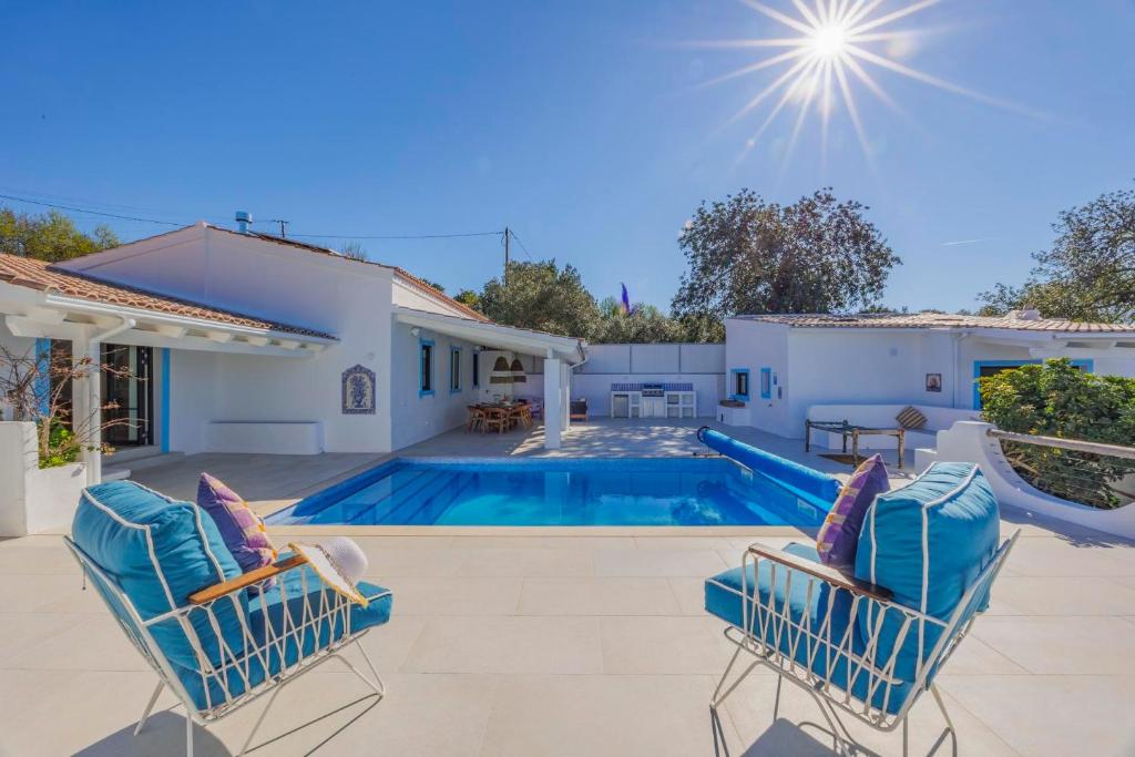 a villa with a swimming pool and two chairs at Vista Azul by Vintage Travel in Loulé