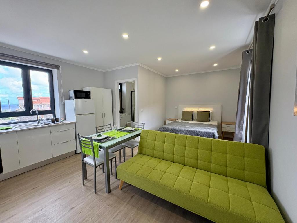 a living room with a green couch and a bed at Maria s Guest House, By OP in Ponta Delgada