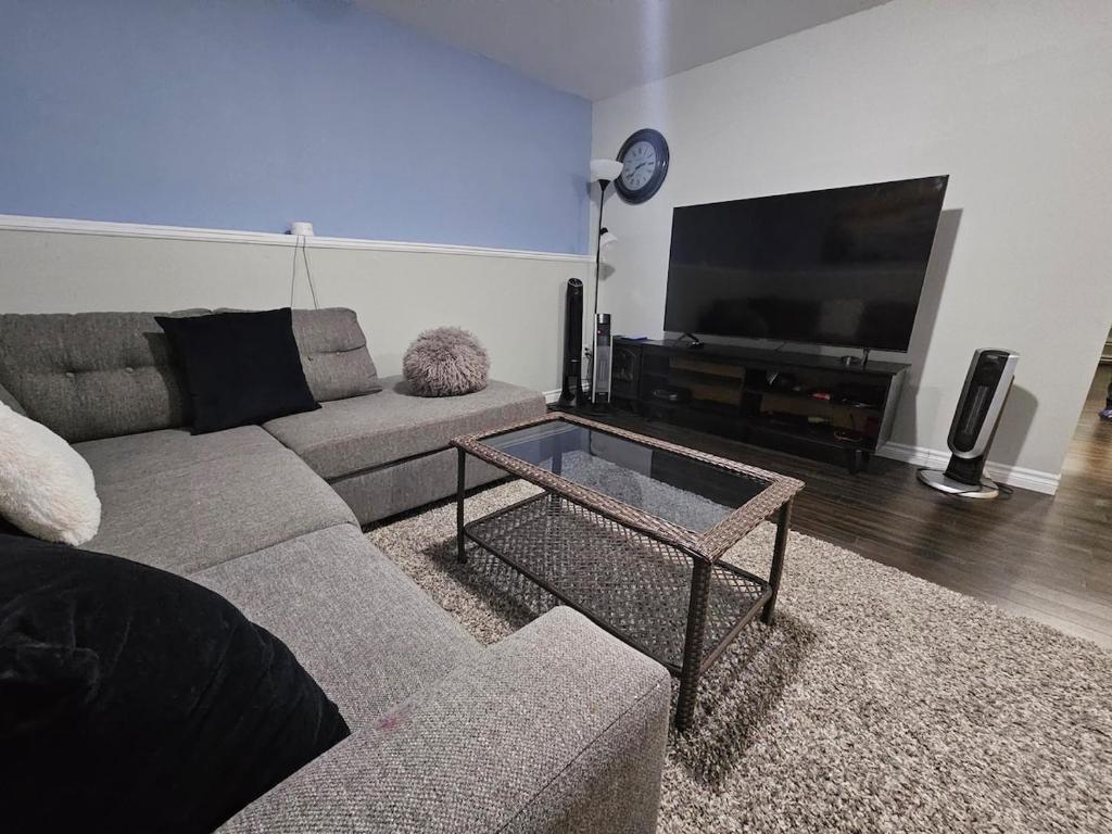a living room with a couch and a flat screen tv at Modern Comfort Haven Near Reversing Falls Bridge Saint John NB in Saint John