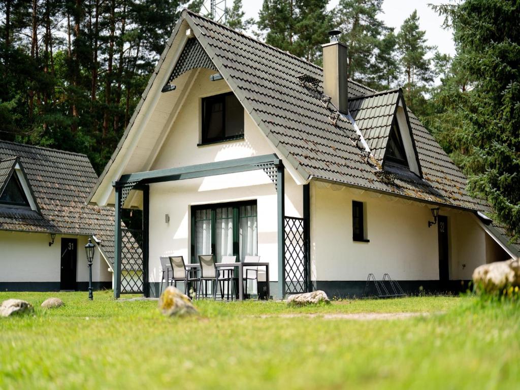 a white house with a black roof at Doppelhaushälften im Naturresort Drewitz in Drewitz