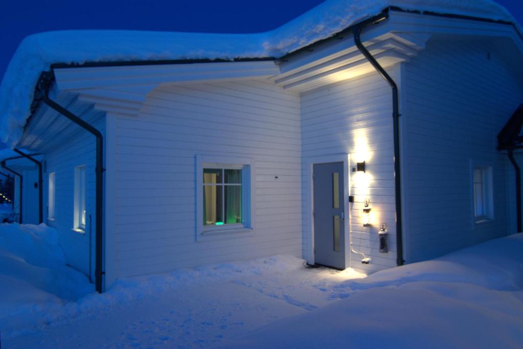 a house with a door in the snow at night at ArcticStay 23A in Pajala