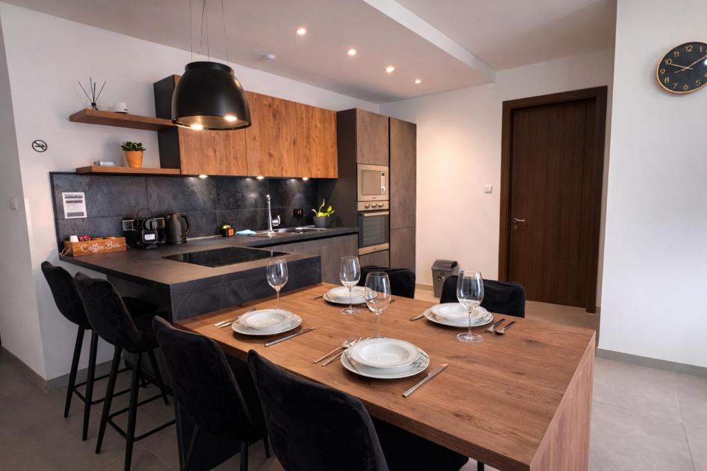 a kitchen with a wooden table with plates and wine glasses at Msida Modern & Bright 2-Bedroom Apartment in Msida