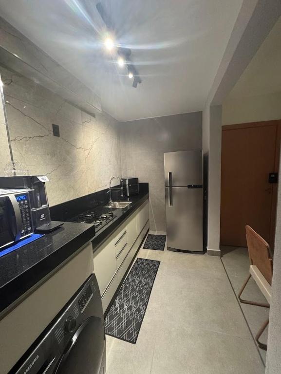 a kitchen with a stainless steel refrigerator and a sink at Vertice House - Copacabana in Uberlândia