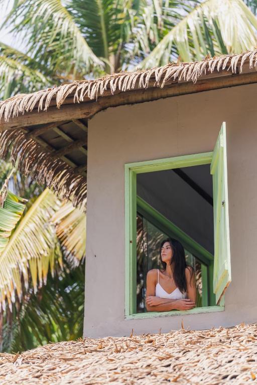 a woman is looking out of a window at Beco das Flores in Mata de Sao Joao