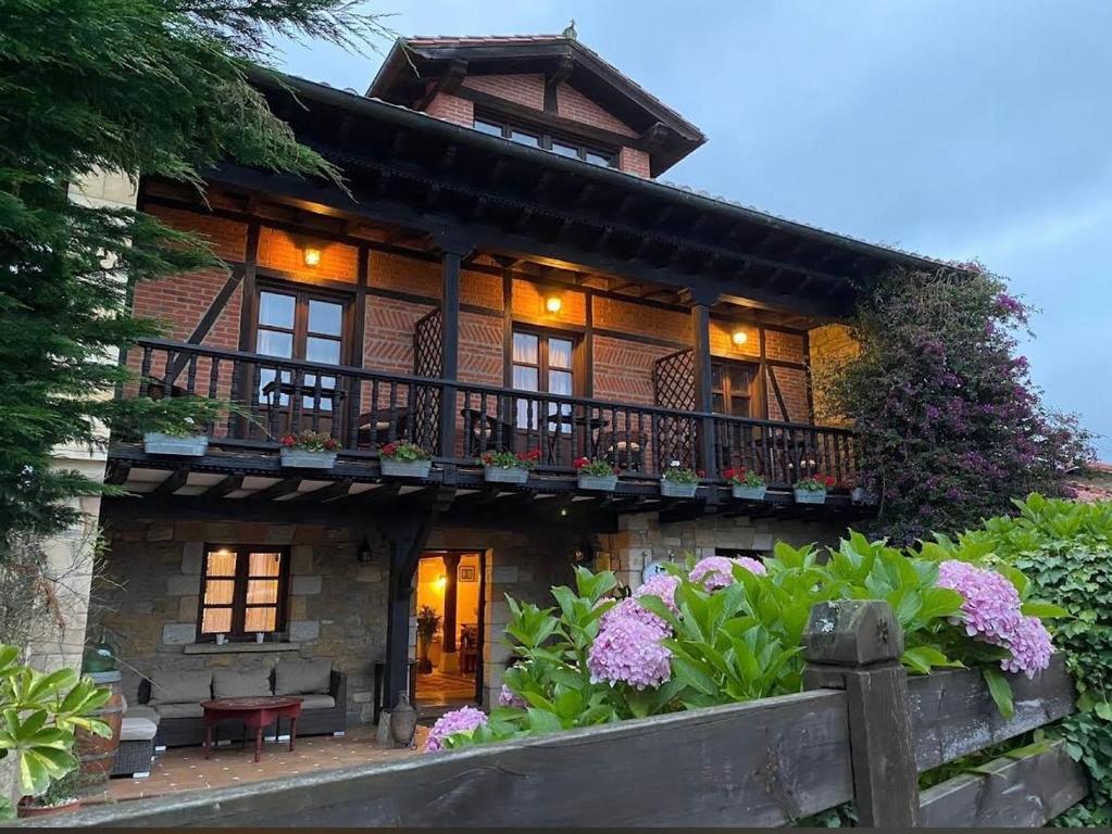 a house with a balcony and flowers in front of it at Posada Rural Valoria in Valoria