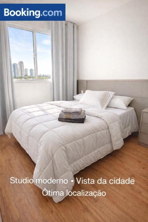 a bedroom with a white bed and a window at Laguna 380 - 1607B - Vista Palácio Tangará in São Paulo