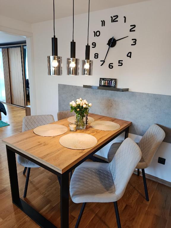 a dining room table with chairs and a clock at Apartmán Forst in Nová Lesná