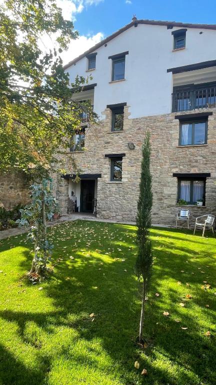 a large stone building with a green yard at Casa La Sendera Alojamiento Rural en La Rioja in Santa Engracia