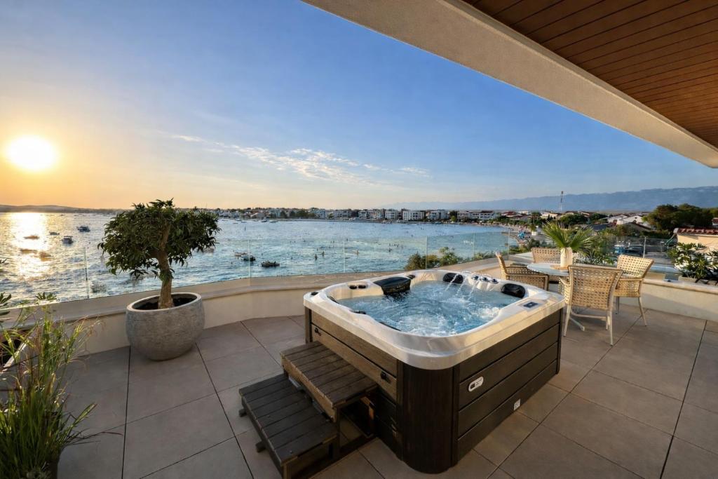 a hot tub on a patio with a view of the water at Apartments Dernaj in Vir