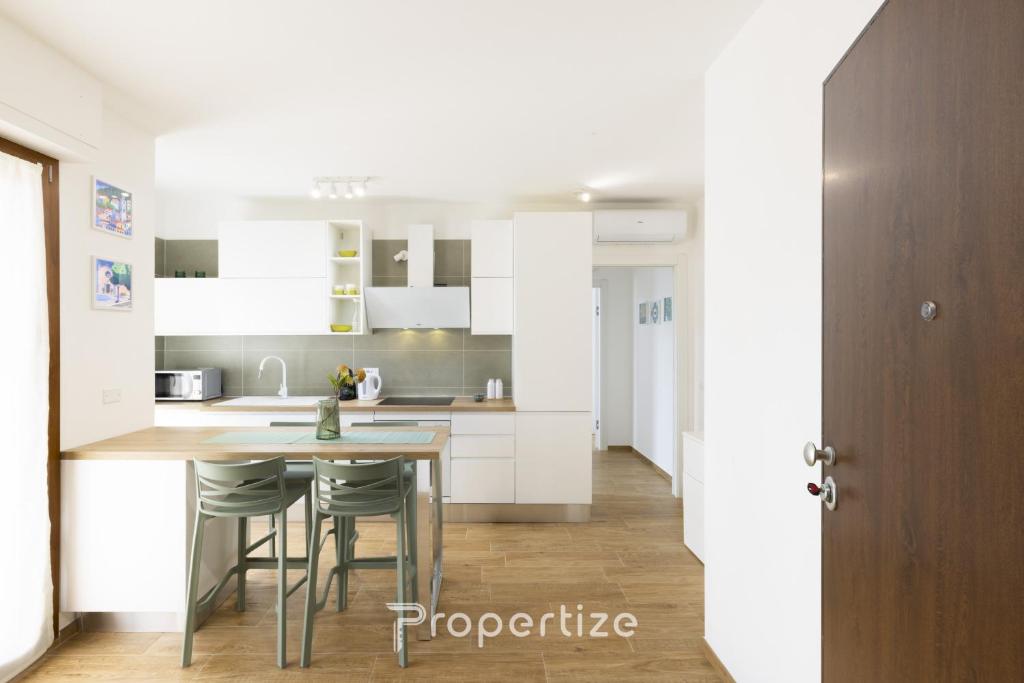 a kitchen with white cabinets and a table and chairs at Verde Appartamento Moderno in Monserrato