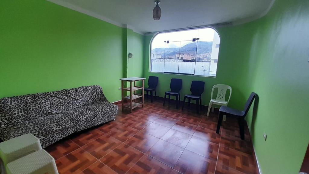 a living room with green walls and a couch and chairs at Kenatural in Cajamarca