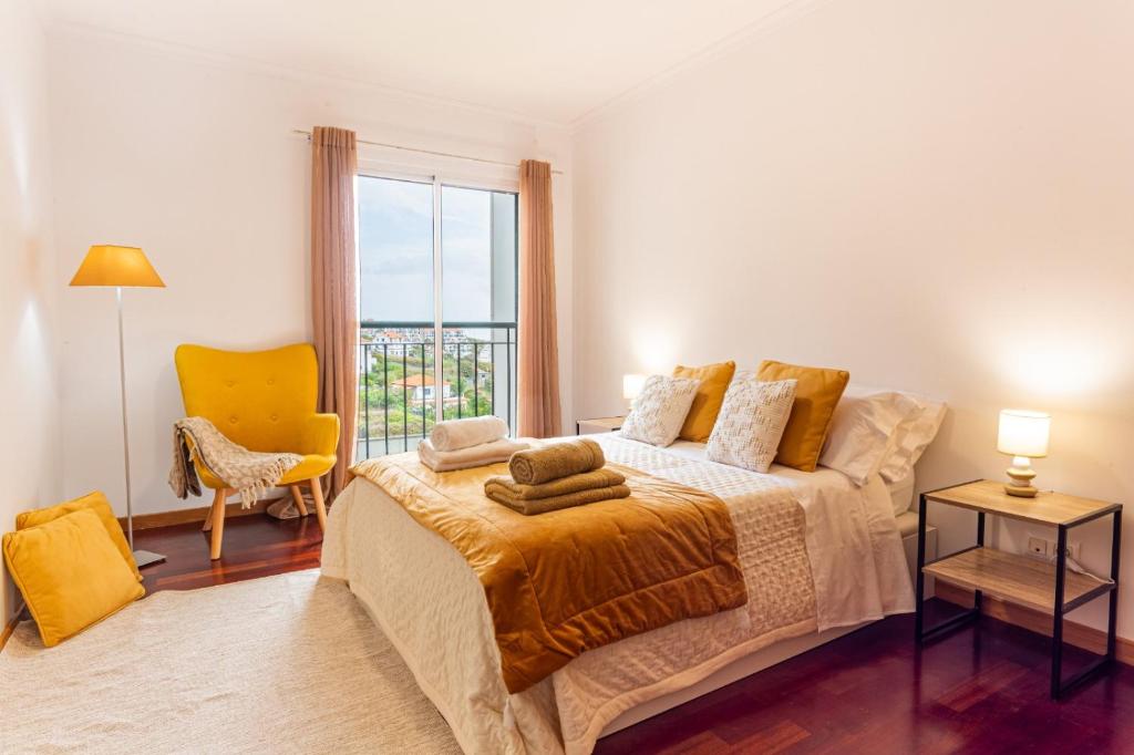 a bedroom with a large bed and a yellow chair at Casa Nobrega in Caniço