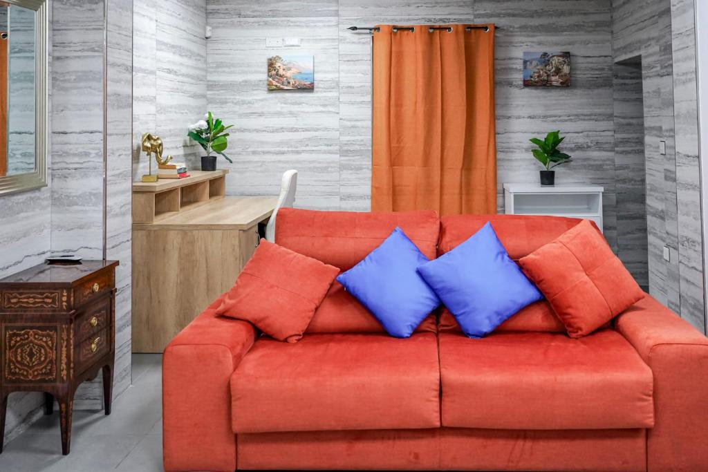 an orange couch with blue pillows in a living room at The Oyster - F in Il-Furjana