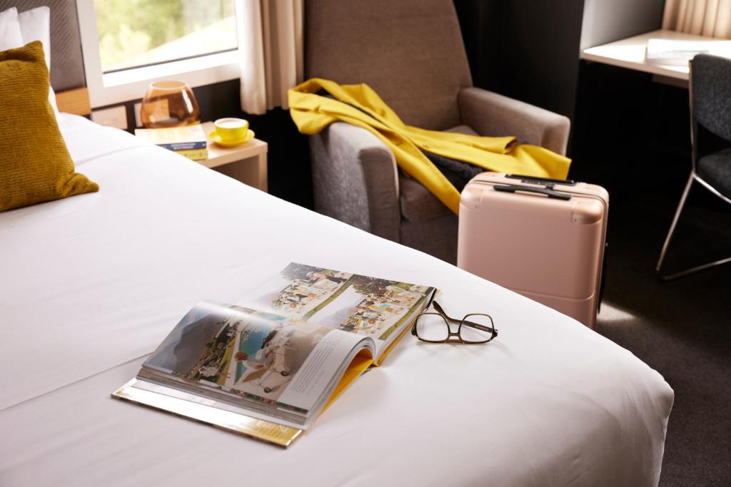 a hotel room with a book and glasses on a bed at WQ Wellington Quarter Hotel in Wellington