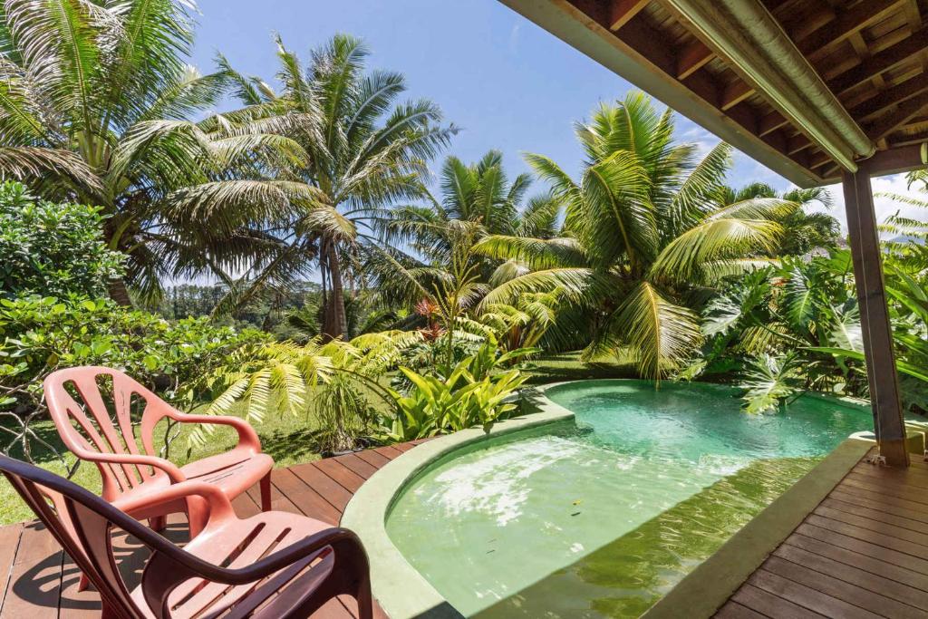 a pool on a deck with two chairs and palm trees at Tropical 2BR Bungalow with Private Pool in Taravao
