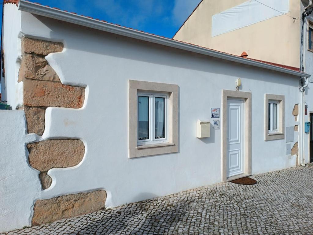 a white house with a stone wall and a door at Casa da Canhota in São Mamede