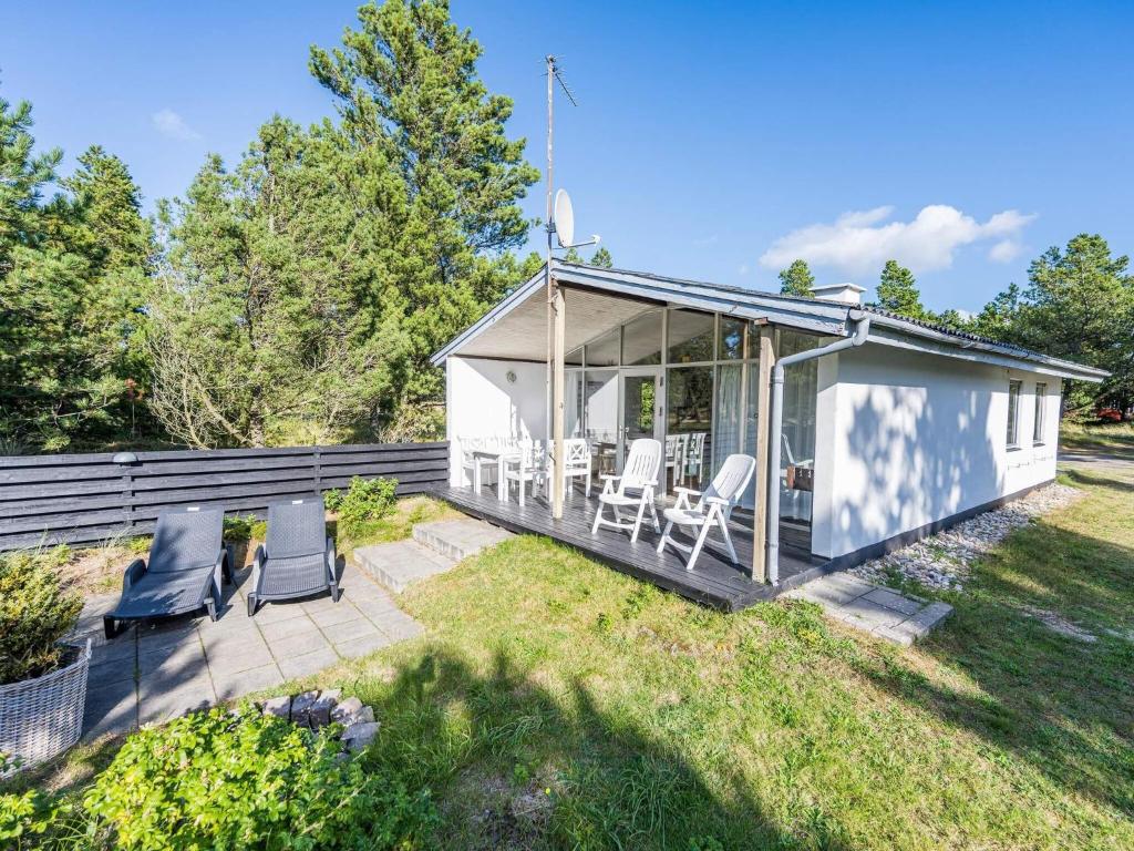 a small white cottage with chairs and a patio at 4 person holiday home in Blåvand in Blåvand
