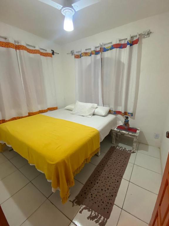 a bedroom with a bed with a yellow blanket at Suítes Xicabacana in Mata de Sao Joao